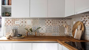 Una cocina con armarios blancos, encimera de madera y un salpicadero estampado.