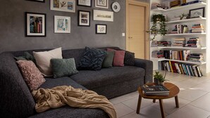 Una sala de estar moderna con un sofá seccional gris, una mesa de centro y una estantería llena de libros.