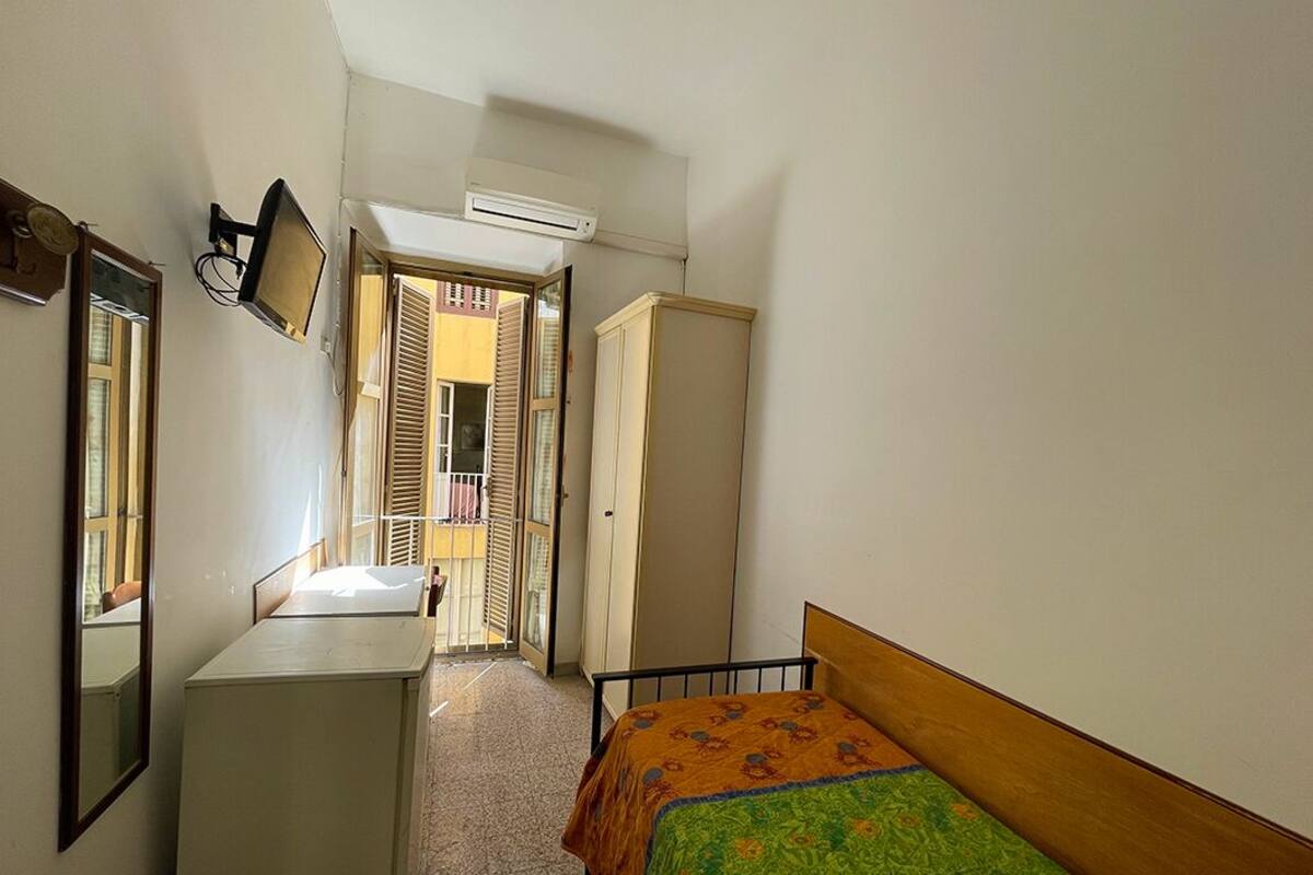 A narrow room with a bed, a desk, and a wardrobe.