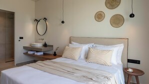 A bedroom with a bed, bedside table, and a wall-mounted vanity with a sink.