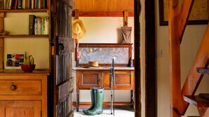 Un intérieur rustique en bois, avec une bibliothèque, un chapeau, une paire de bottes vertes et une échelle.