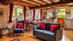 Un salon confortable avec un canapé, des fauteuils et une table à manger. Il y a également un coin cuisine avec des placards et une fenêtre.