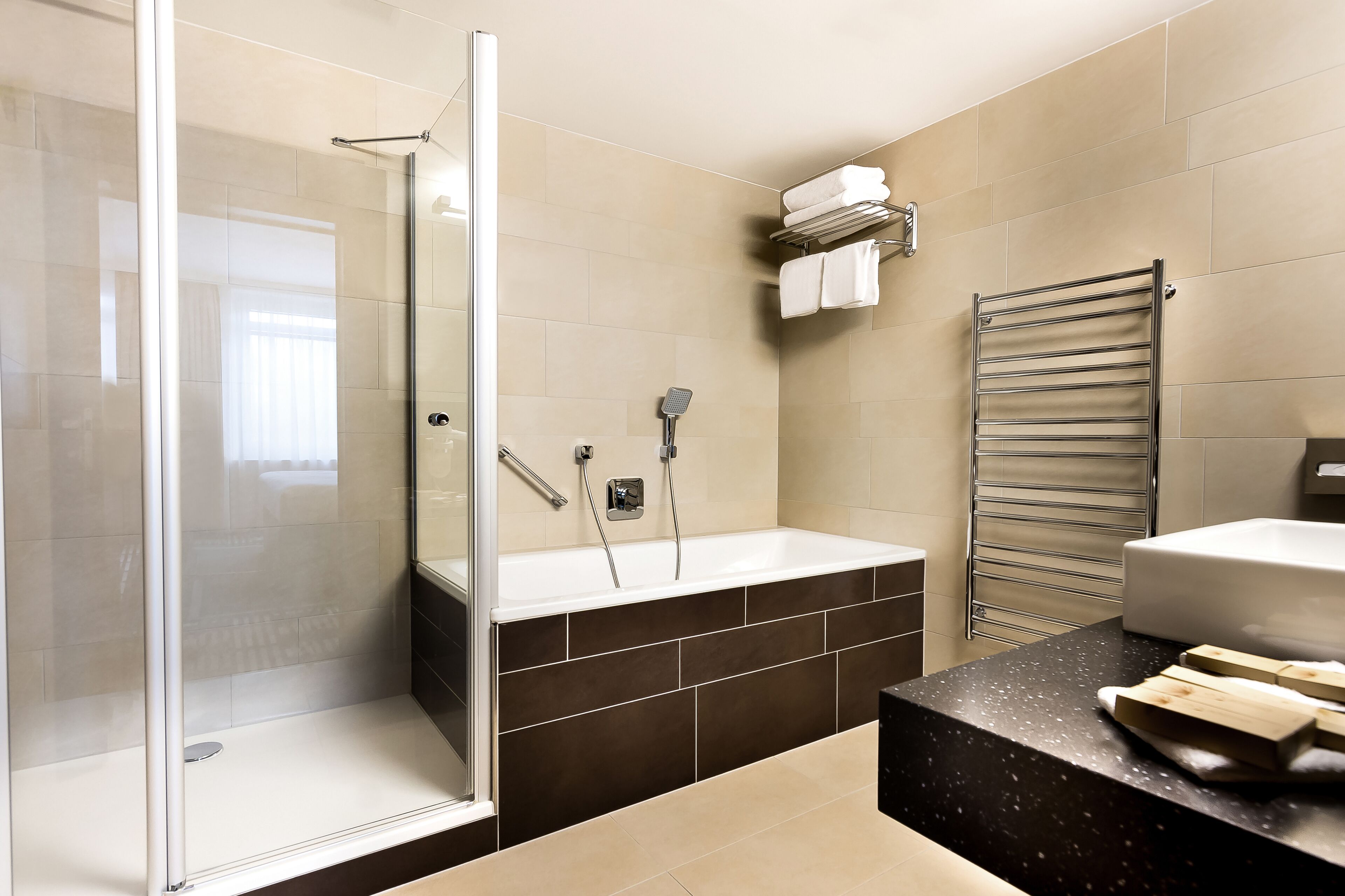 A modern bathroom with a glass-enclosed shower, a bathtub, and a sink.