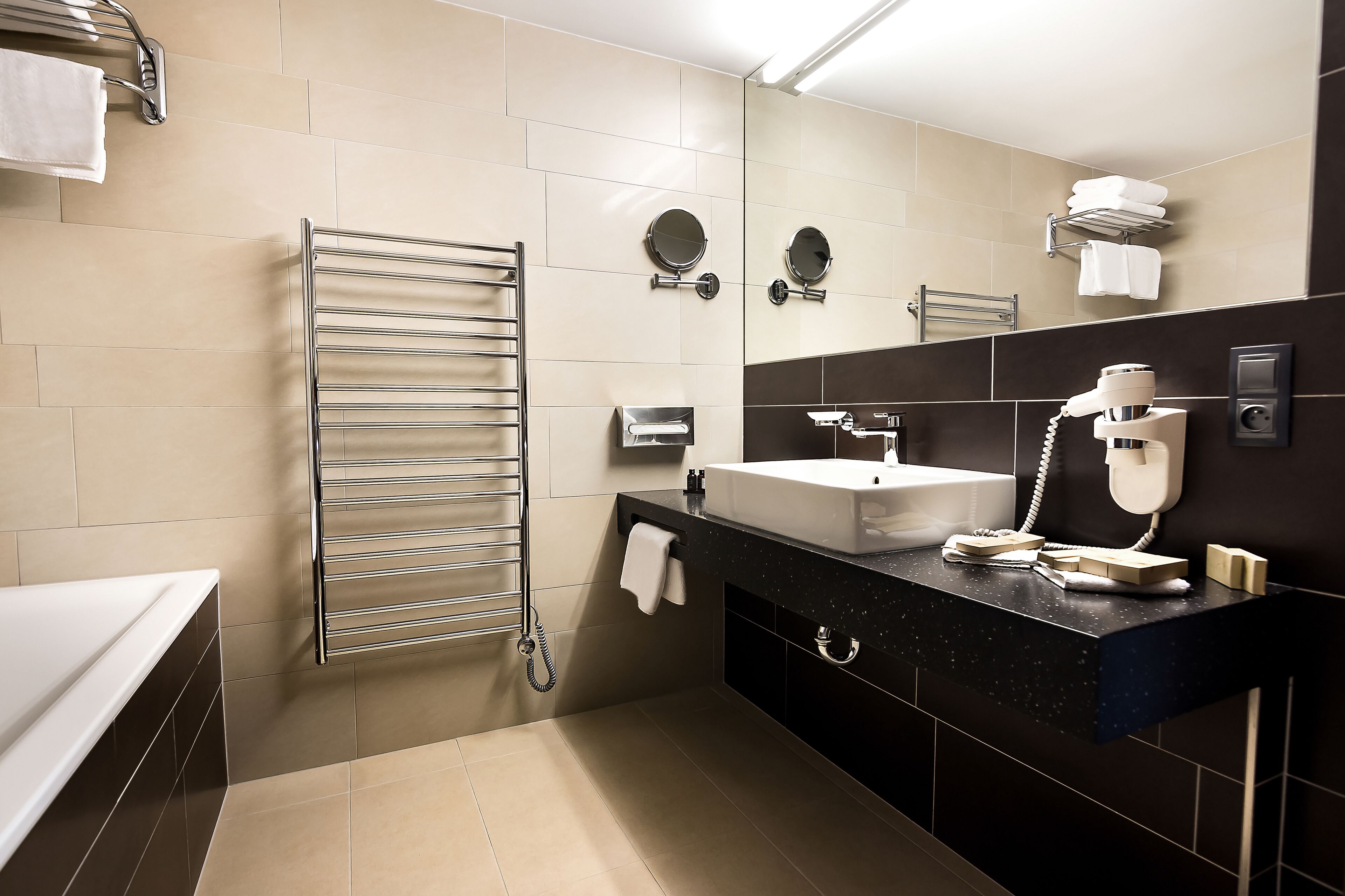 A modern bathroom with a sink, mirror, towel rack, and a hairdryer.