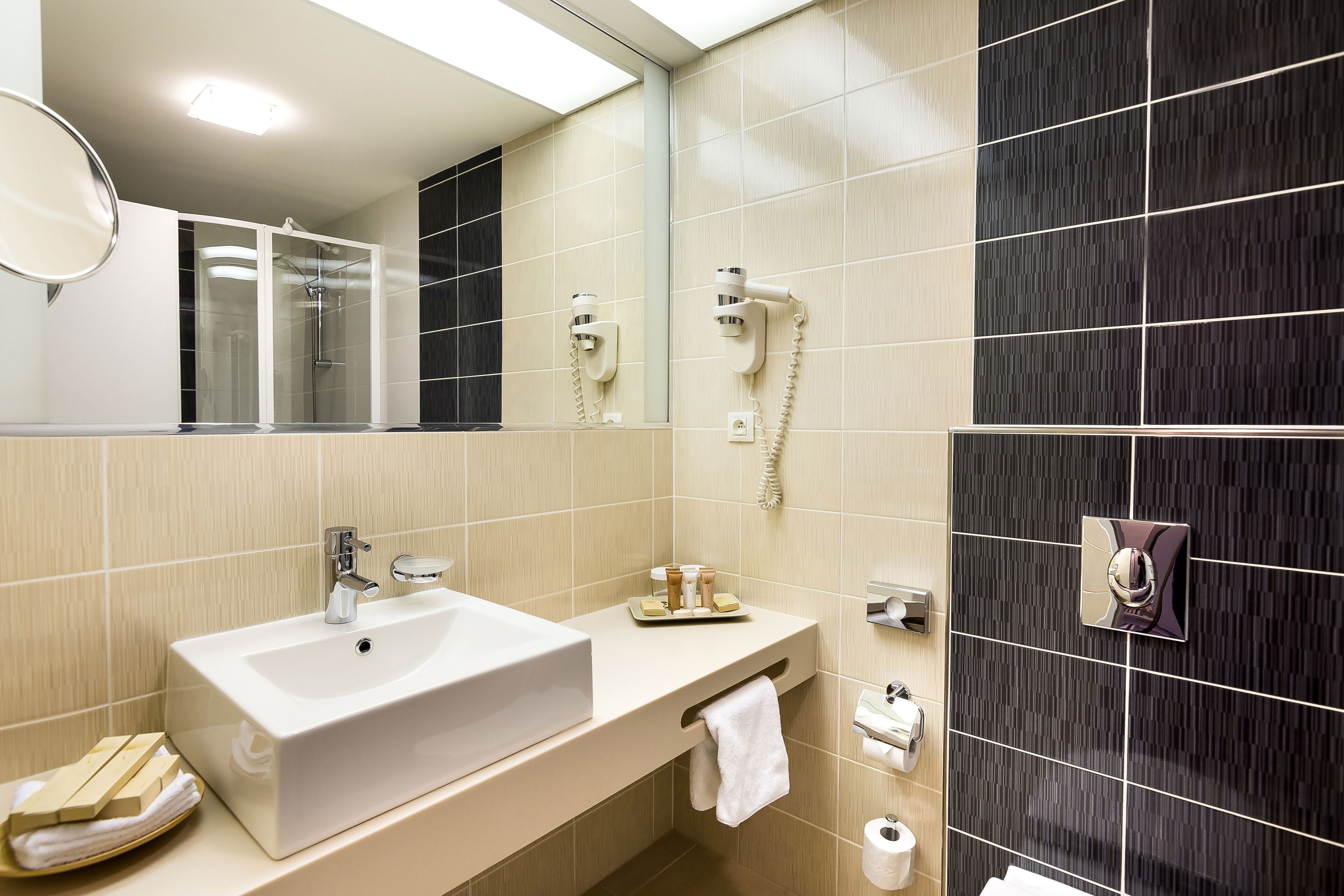 Ein modernes Badezimmer mit einem großen Waschbecken, einem Spiegel, einem Handtuchhalter und einer Dusche.