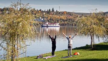 Two people on a grassy area by a lake with a boat in the background.