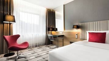 Une chambre d’hôtel avec un grand lit, un bureau, une chaise et un miroir.