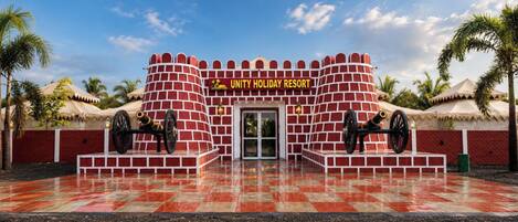 A brick structure with a sign reading 'UNITY HOLIDAY RESORT' and two cannons in front.