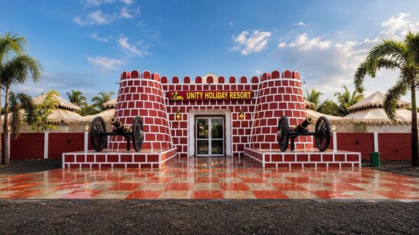 A brick structure with a sign reading 'UNITY HOLIDAY RESORT' and two cannons in front.