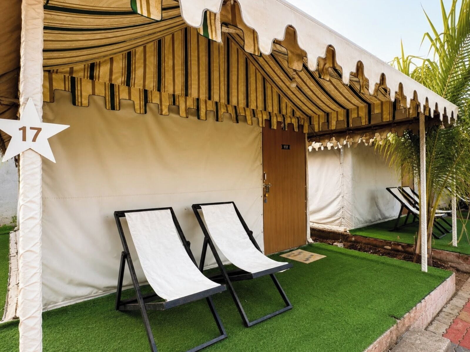 Un espacio con toldo, dos sillones de relax, césped artificial y una puerta marcada con el número 17.