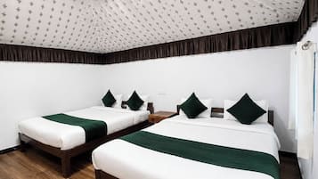 A hotel room with two single beds, each with a green accent pillow, a wooden nightstand, and a patterned ceiling.