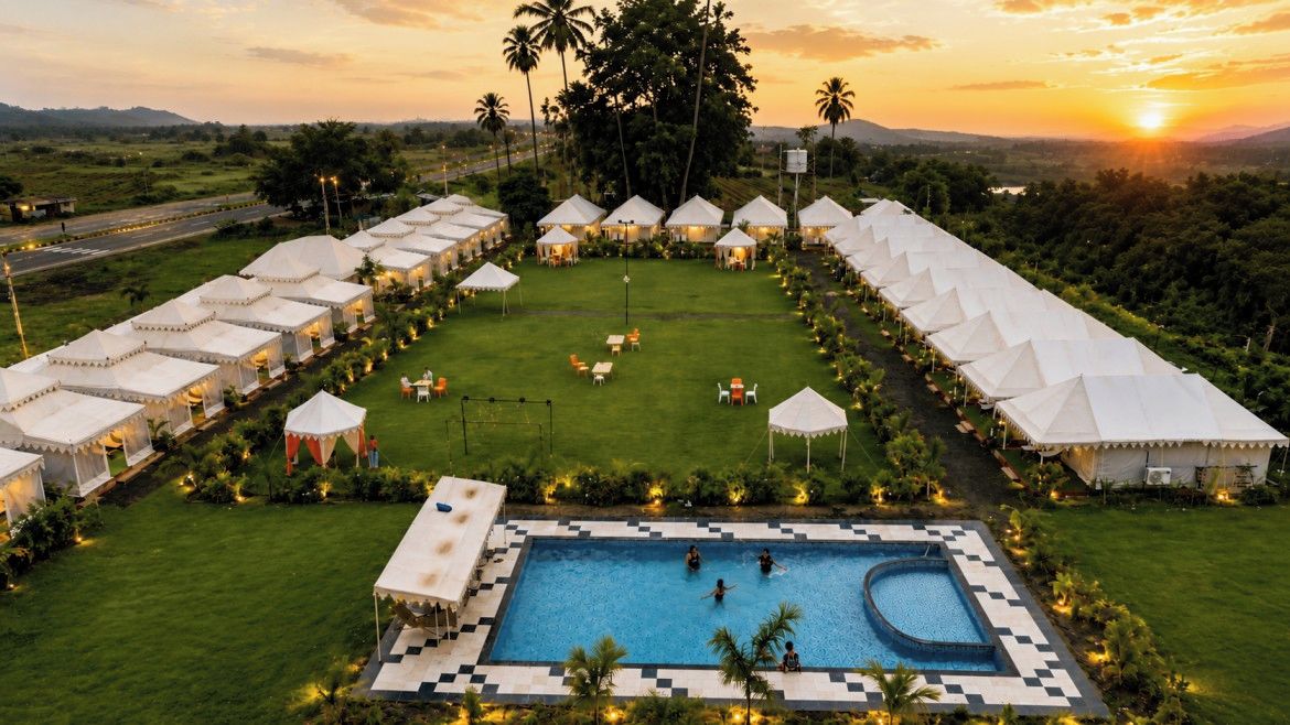 A resort with multiple tents, a swimming pool, and a grassy lawn.