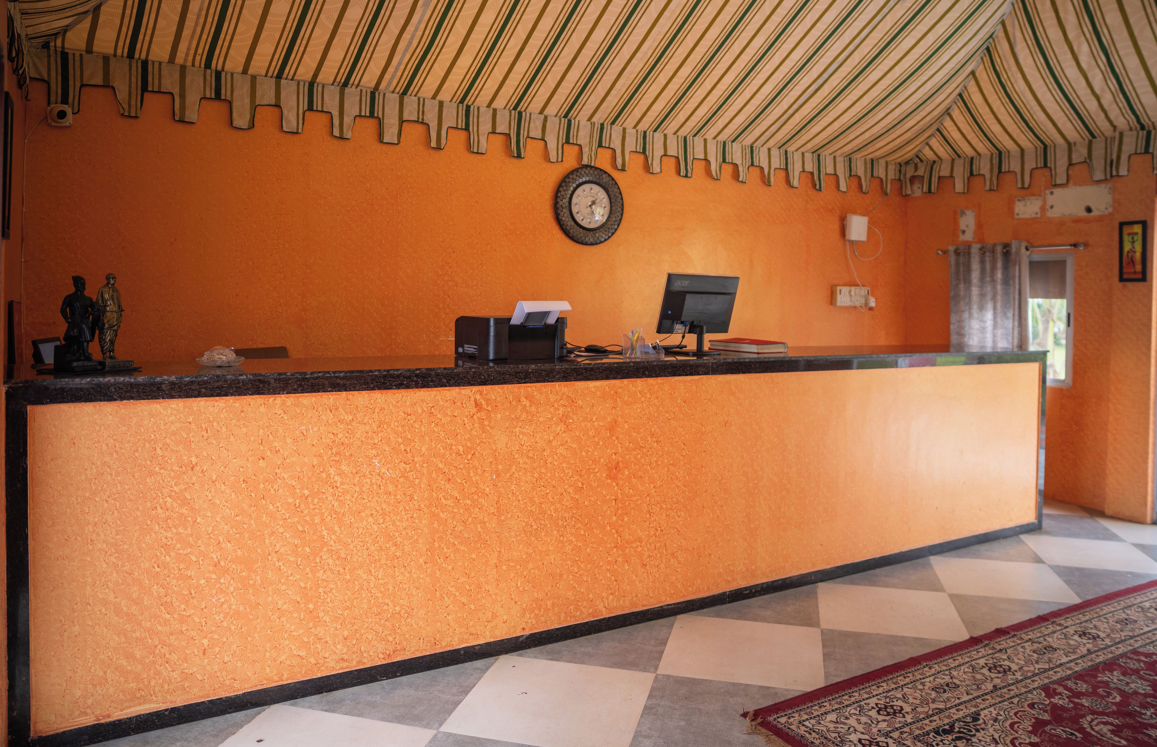 A reception desk with a clock, a computer, and a telephone.