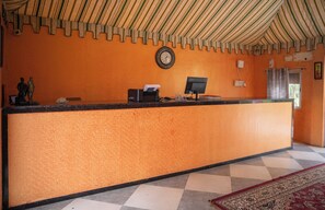 En receptionsdisk med en klocka, en dator och en telefon.