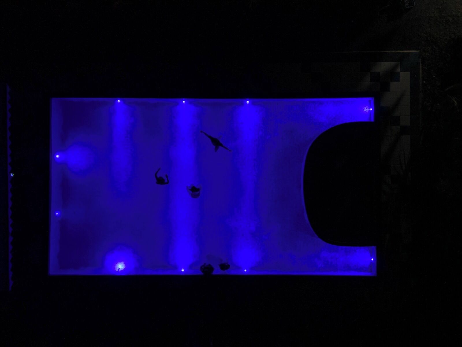 Une pièce sombre éclairée par une lumière bleue, dans laquelle on distingue la silhouette d’une personne.