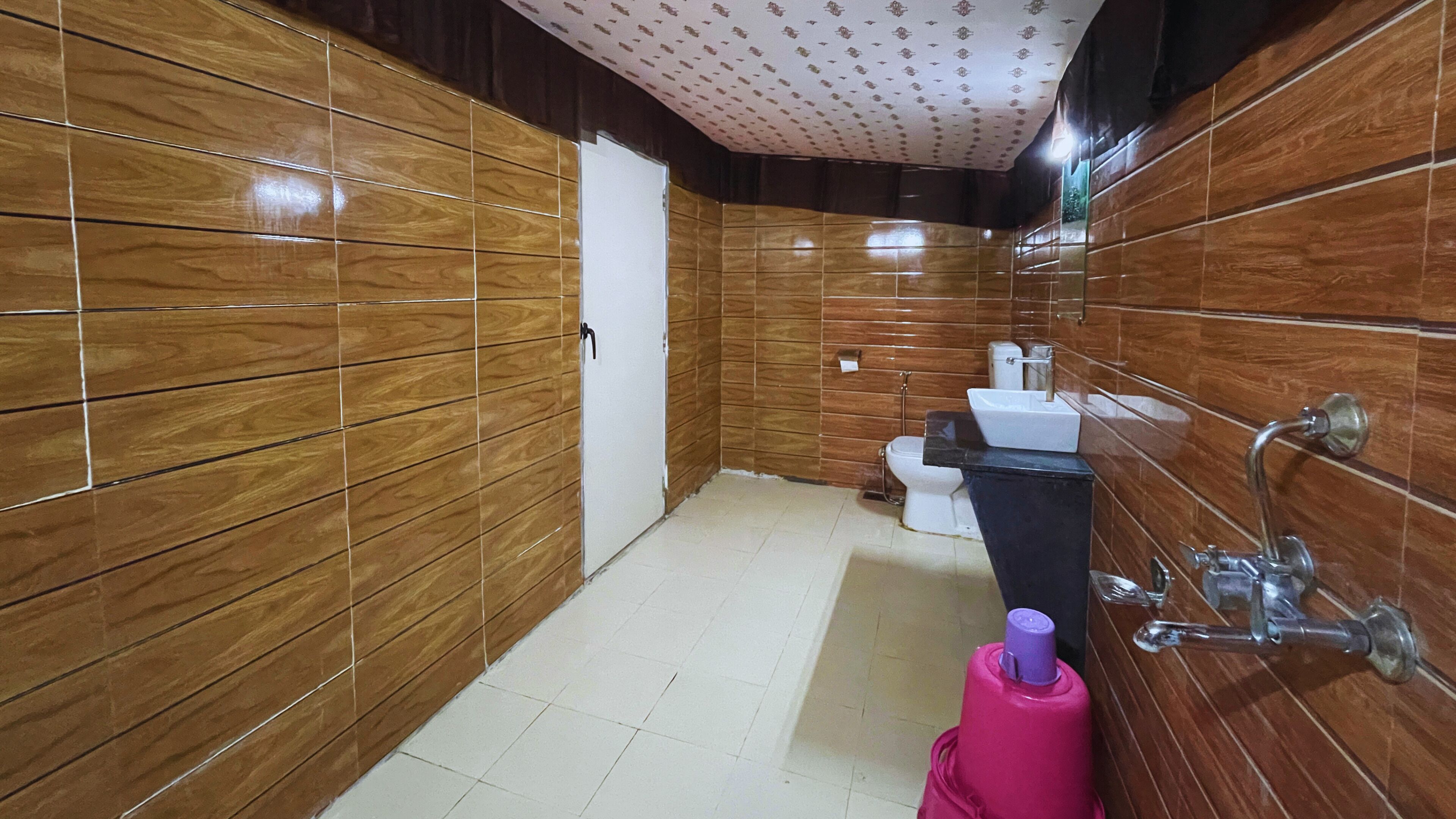 A bathroom with wooden paneling, a toilet, a sink, and a shower.