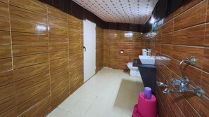 A bathroom with wooden paneling, a toilet, a sink, and a shower.