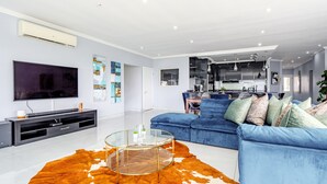 Uma sala de estar moderna com um sofá azul, uma mesa de centro de vidro e um tapete de couro de vaca.