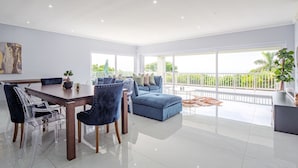 Uma sala ampla com uma mesa de jantar, cadeiras e um sofá azul.