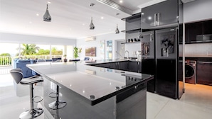 Uma cozinha moderna com uma ilha central, armários pretos e eletrodomésticos de aço inoxidável.