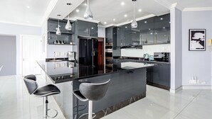 Cozinha moderna com ilha central, banquetas e luminárias pendentes.