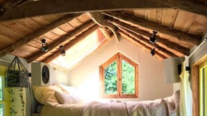 Une petite pièce avec un lit superposé, une petite fenêtre et une échelle.