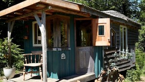 Une cabane rustique dotée d’une véranda, d’une chaise en bois et d’une petite table.