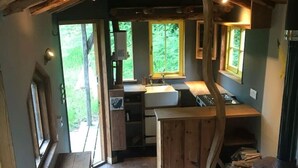 L’intérieur d’un chalet rustique comprenant une cuisine, une cheminée et une grande fenêtre.