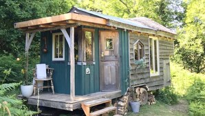 Une cabane rustique dotée d’un porche, d’une petite terrasse et d’une porte d’entrée.