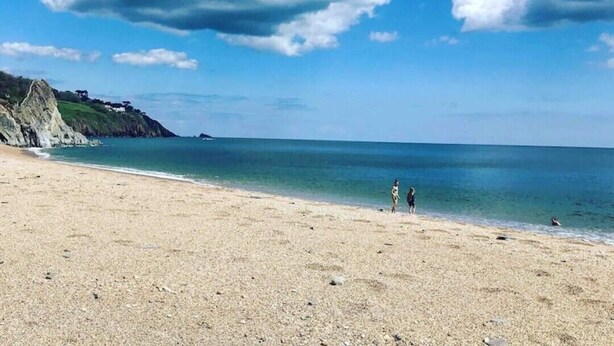 Une plage avec un ciel dégagé et quelques nuages.
