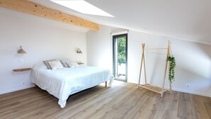 Una camera da letto con un letto, travi in legno, un lucernario, una finestra e un espositore per piante.