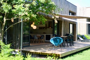 A modern house with a deck, dining area, and lounge chairs. - Bioclimatic home with a spectacular panoramic view (Messanges)