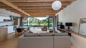 Un soggiorno moderno con soffitto in legno, angolo da pranzo e divano.