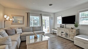 A modern living room with a sectional sofa, a glass coffee table, a wooden cabinet, and a flat-screen TV.