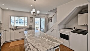 A modern kitchen with white cabinetry, a marble countertop, and a built-in oven.