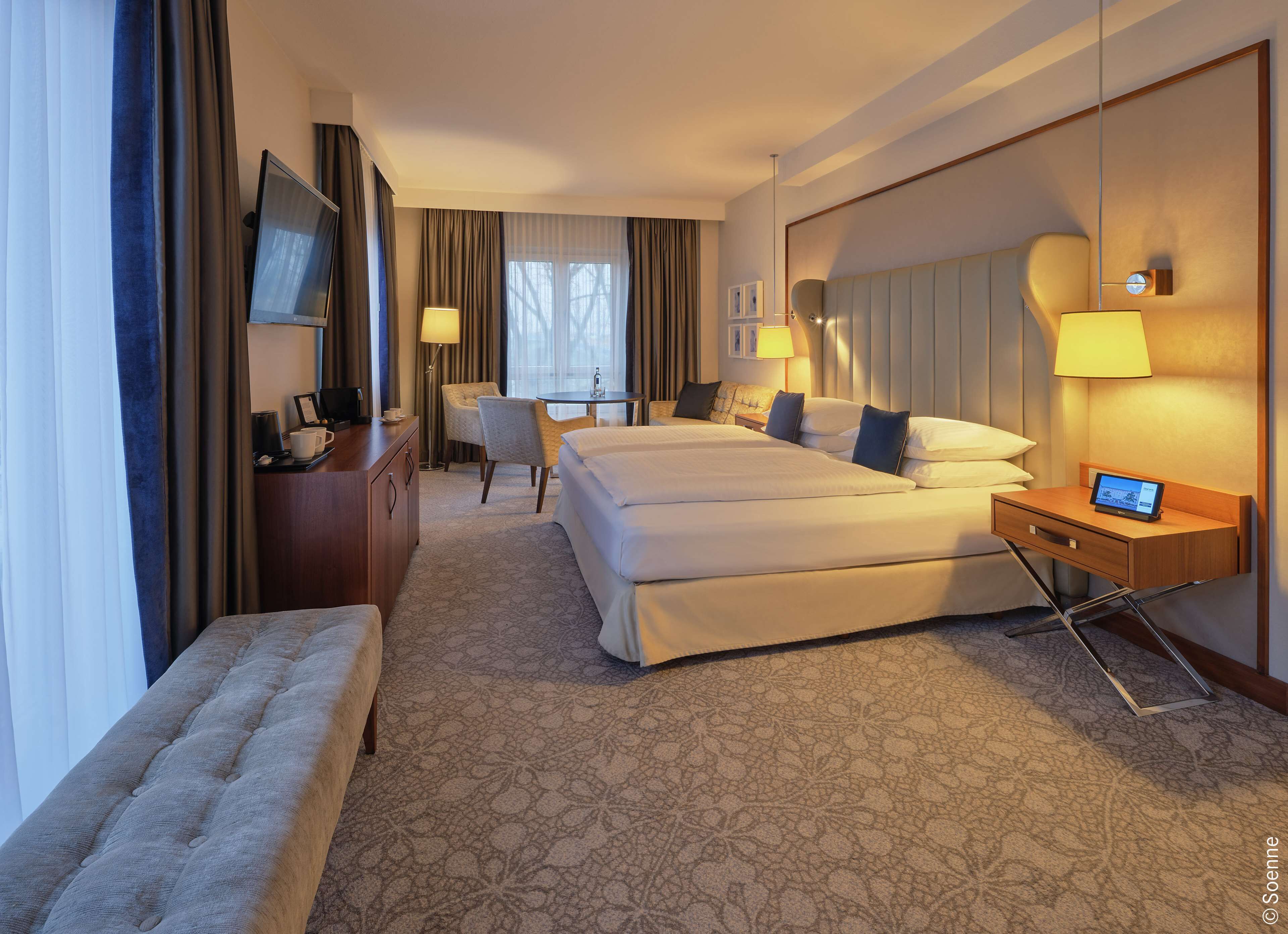A hotel room with a large bed, a desk, a chair, and a TV.