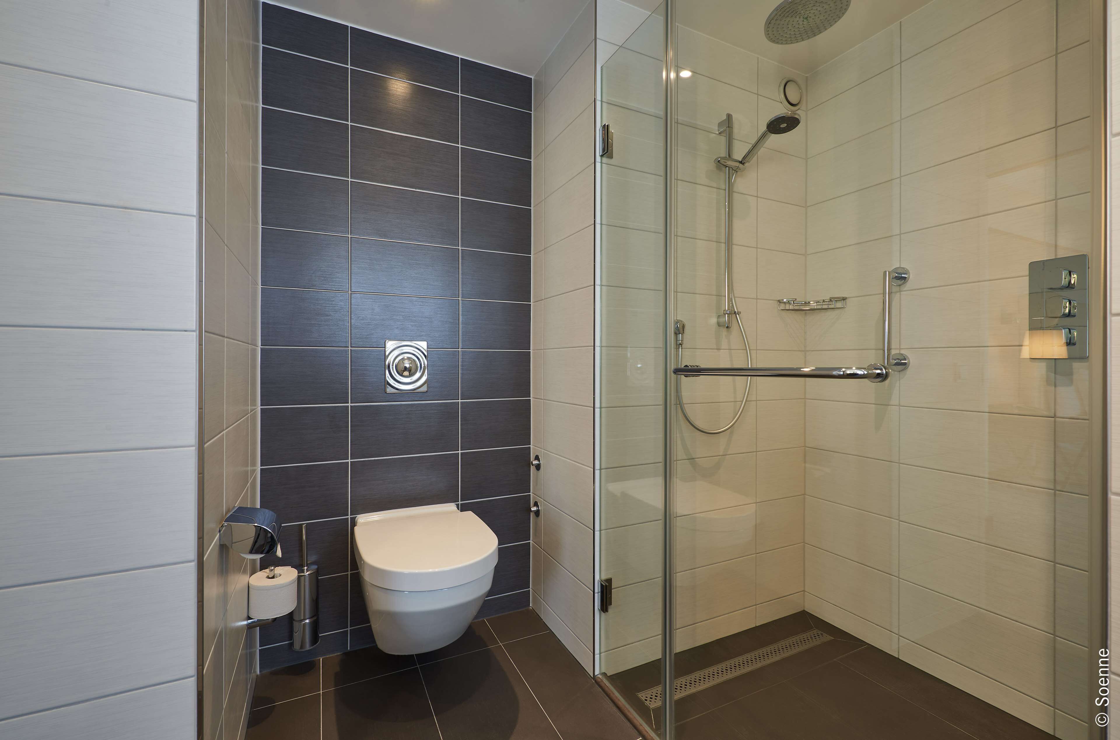 Ein modernes Badezimmer mit Toilette, Dusche und einer gläsernen Duschkabine.