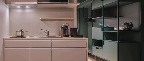 A modern kitchen with a built-in microwave, a kettle, and a sink.