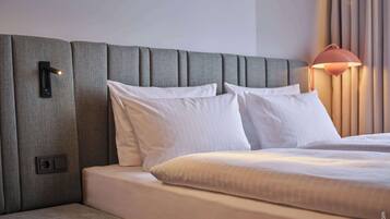 Ein Hotelzimmer mit einem großen Bett, einem Kopfteil, einem Nachttisch und einer Lampe.