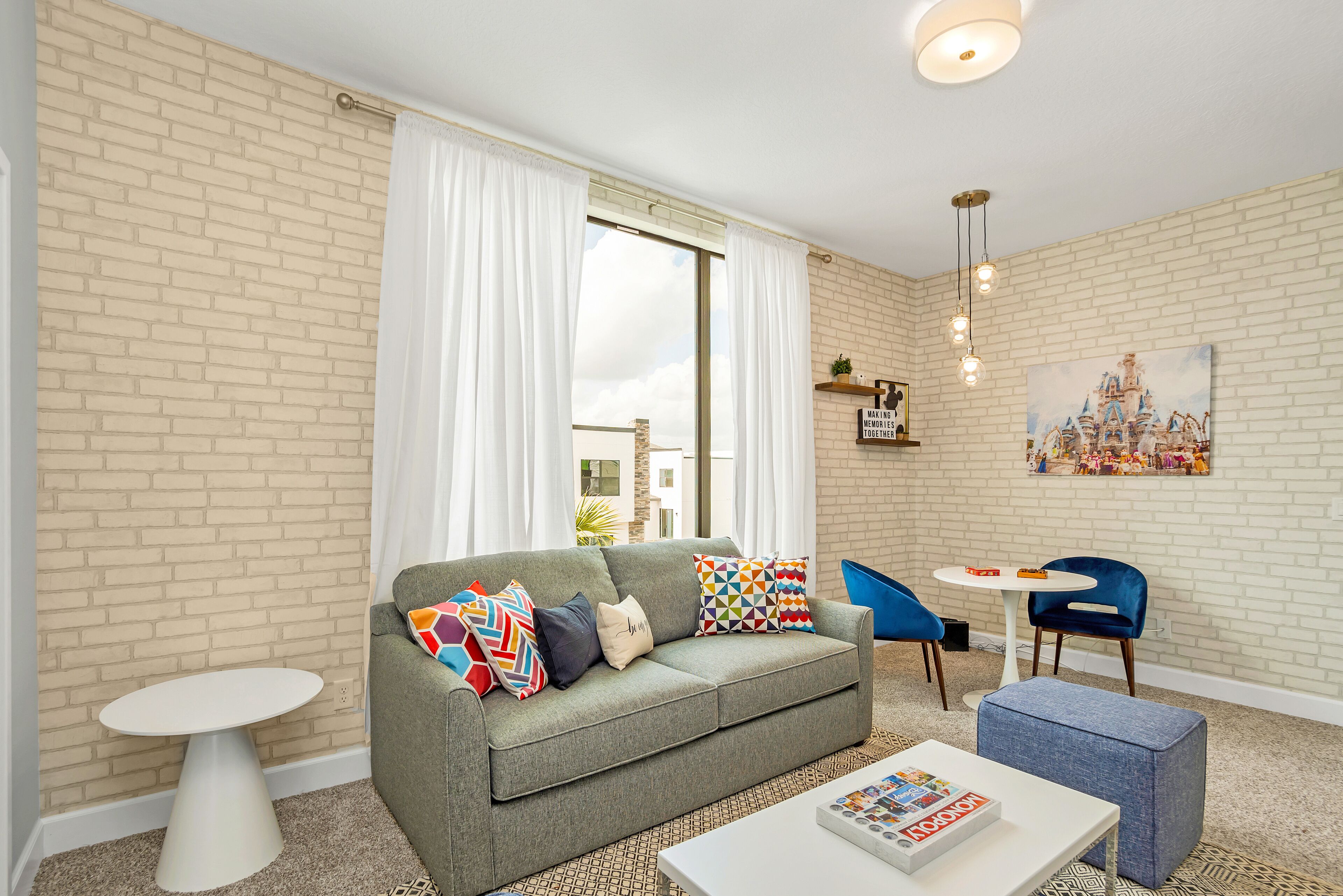 A modern living room with a grey sofa, colorful cushions, a white coffee table, and a blue chair.
