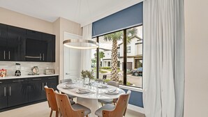 A modern kitchen with black cabinets, a white countertop, and a dining area with a round table and chairs. - Villa Domani Resort (Davenport)