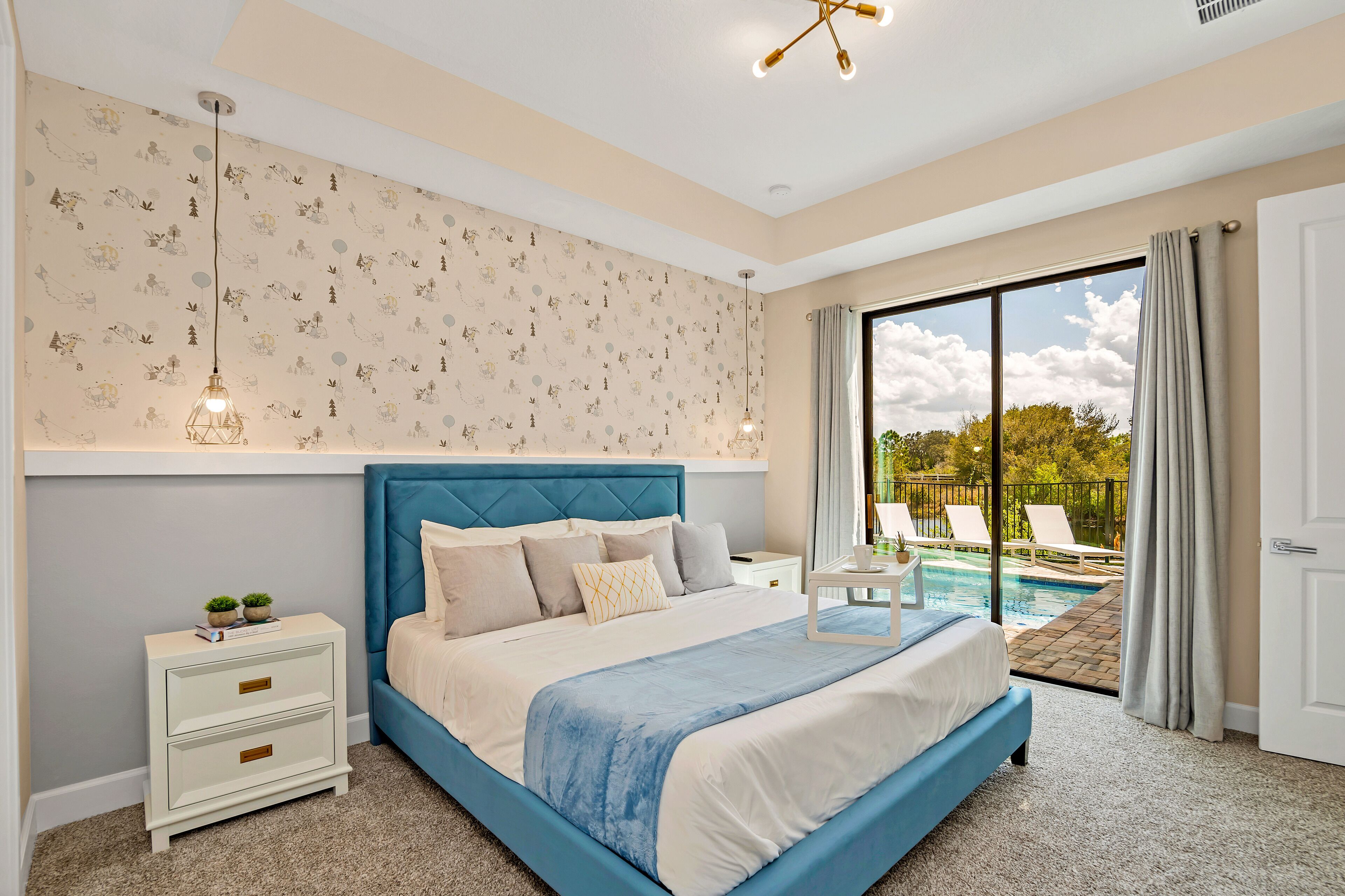 A bedroom with a large bed, a nightstand, a wall-mounted light, and a view of an outdoor swimming pool.