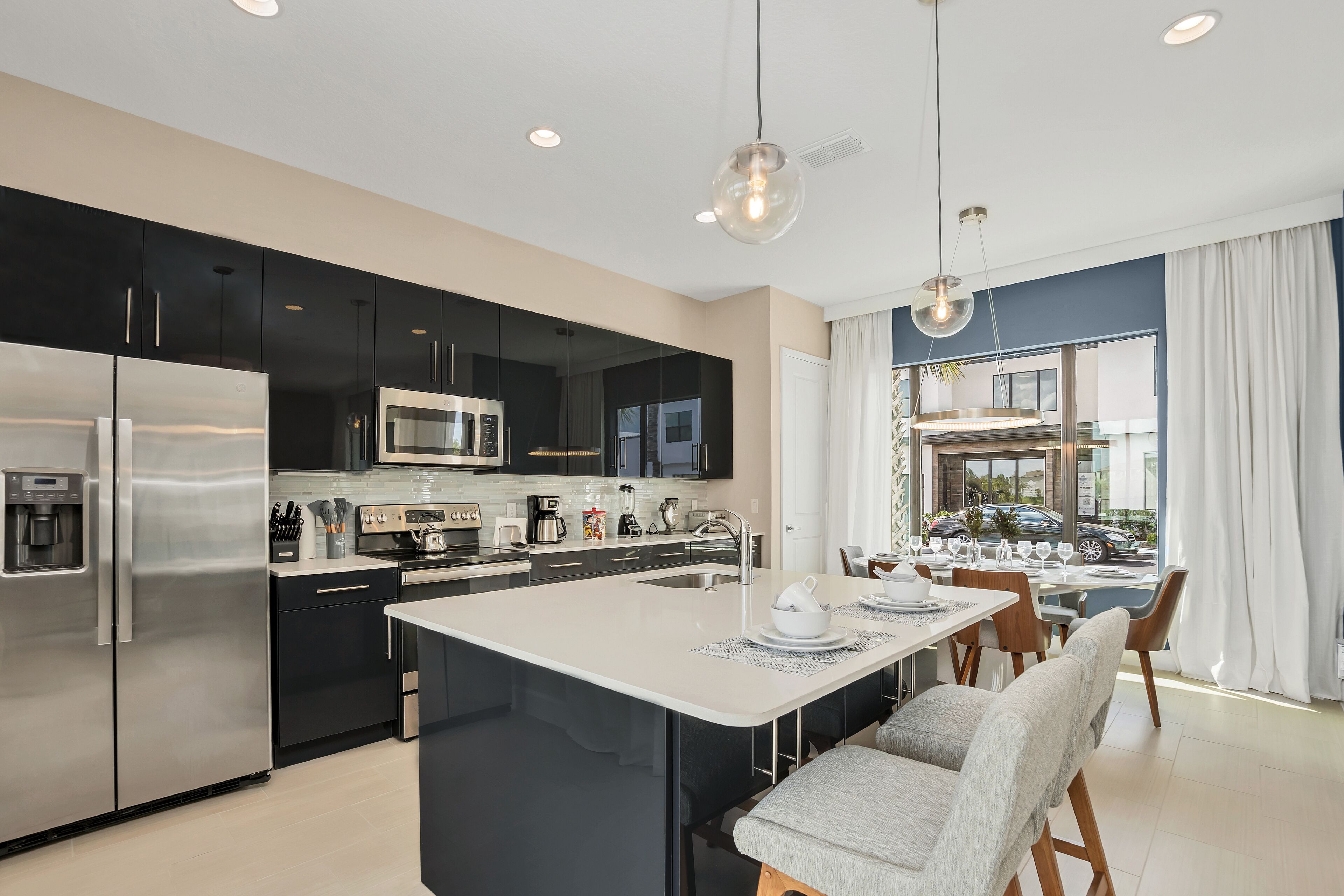 A modern kitchen with a central island, stainless steel appliances, and a dining area with a view.