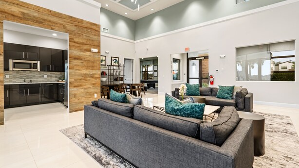 A spacious living area with a grey sofa, a dining table, and a kitchen with modern appliances. - Villa Domani Resort (Davenport)