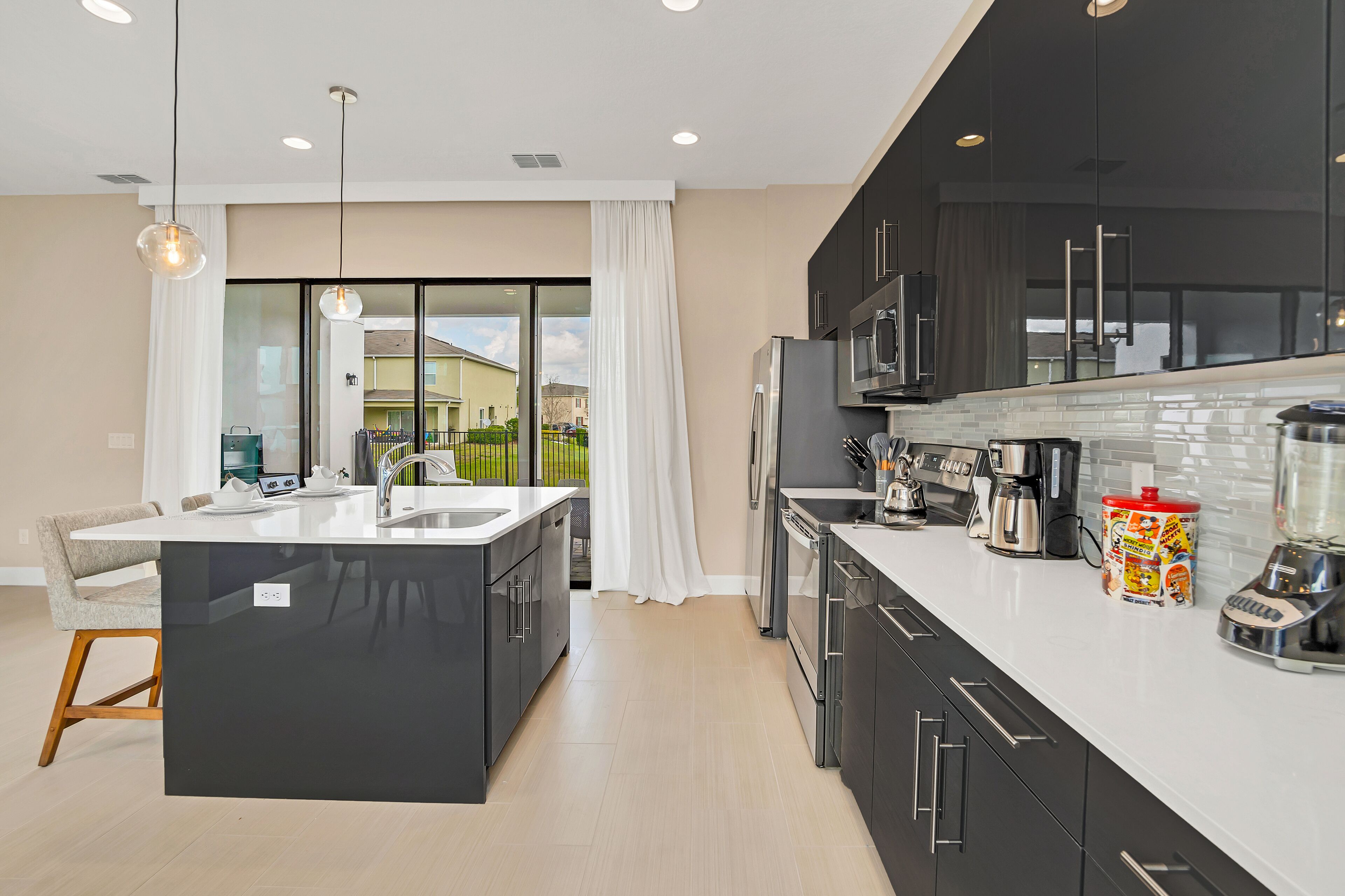 A modern kitchen with a central island, black cabinets, and stainless steel appliances.