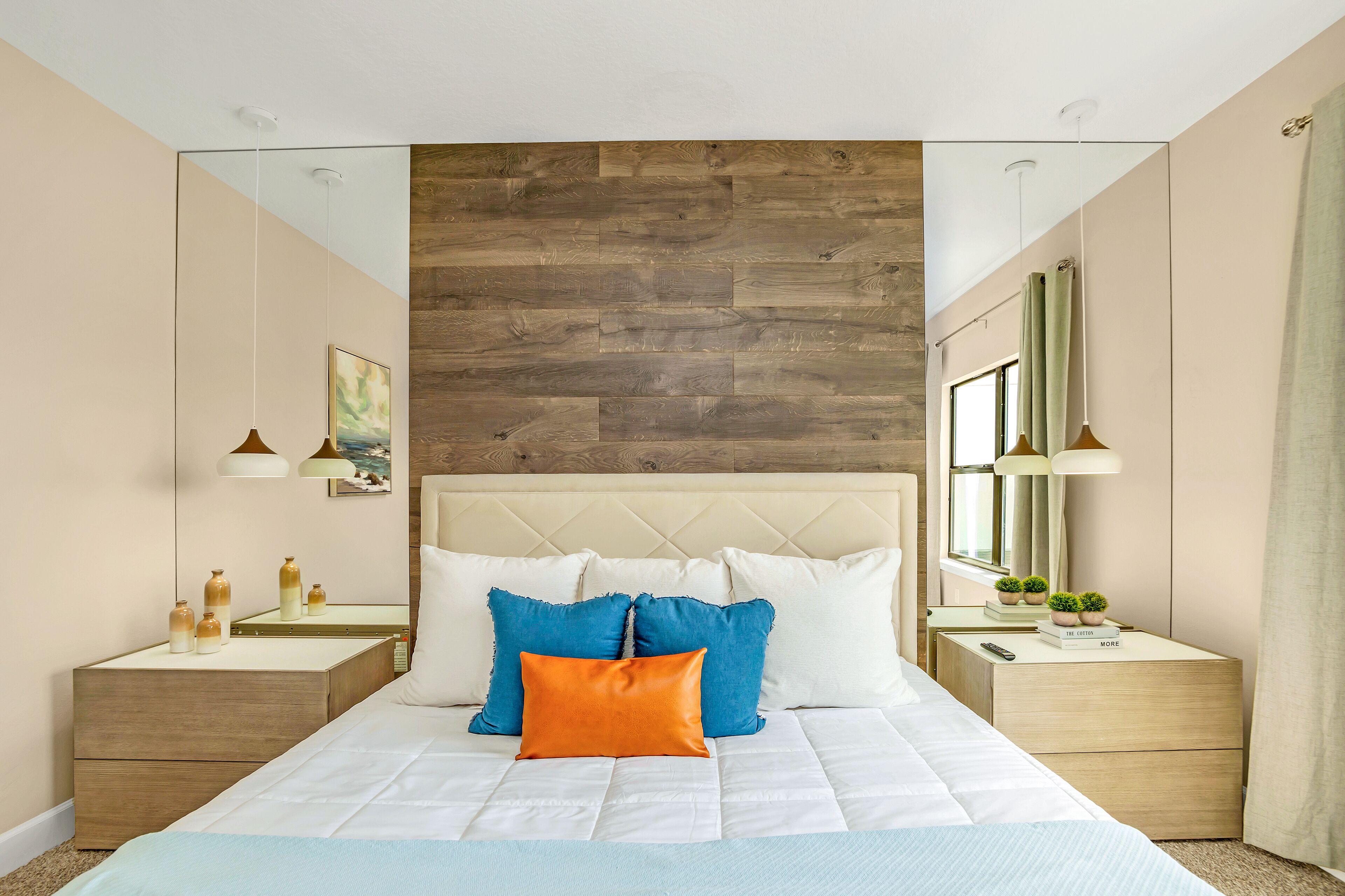 A modern bedroom with a large bed, wooden headboard, bedside tables, and a mirror.