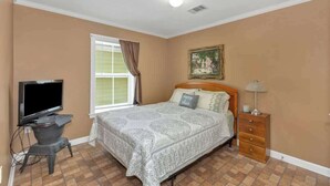 A bedroom with a bed, a television, a desk, and a window with curtains. - *Cottage #4 @ Fisherman's Landing (boat shelter)* (Langston)