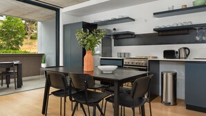 A modern kitchen with a dining area, featuring a large island, black chairs, and a potted plant. - Modern 3-Bedroom in the Heart of Bo-Kaap - Netflix (Cape Town)