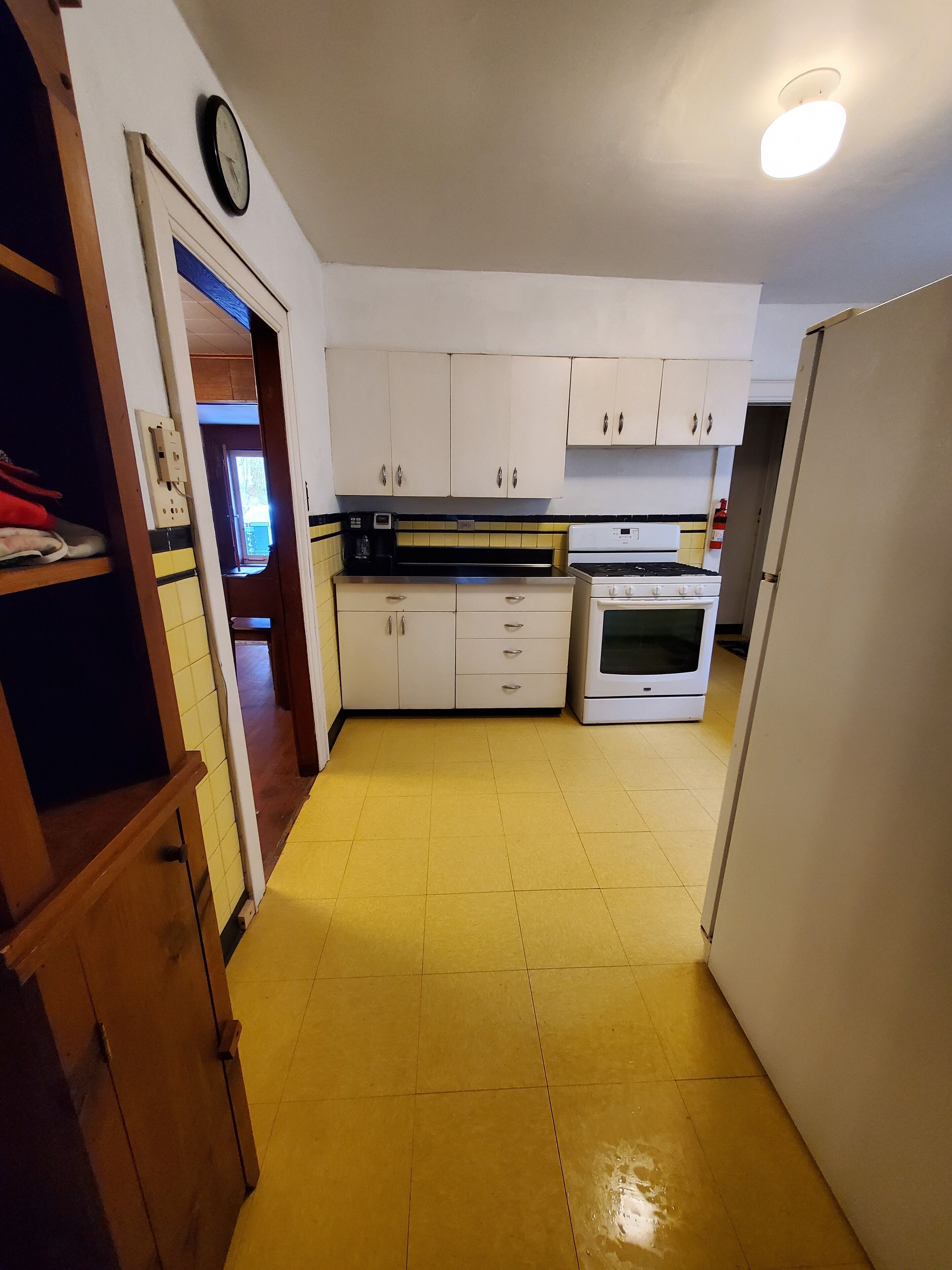 A kitchen with white cabinets, a stove, and a refrigerator.