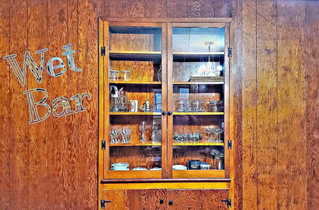 Een houten kast met glazen deuren, gevuld met keukengerei.